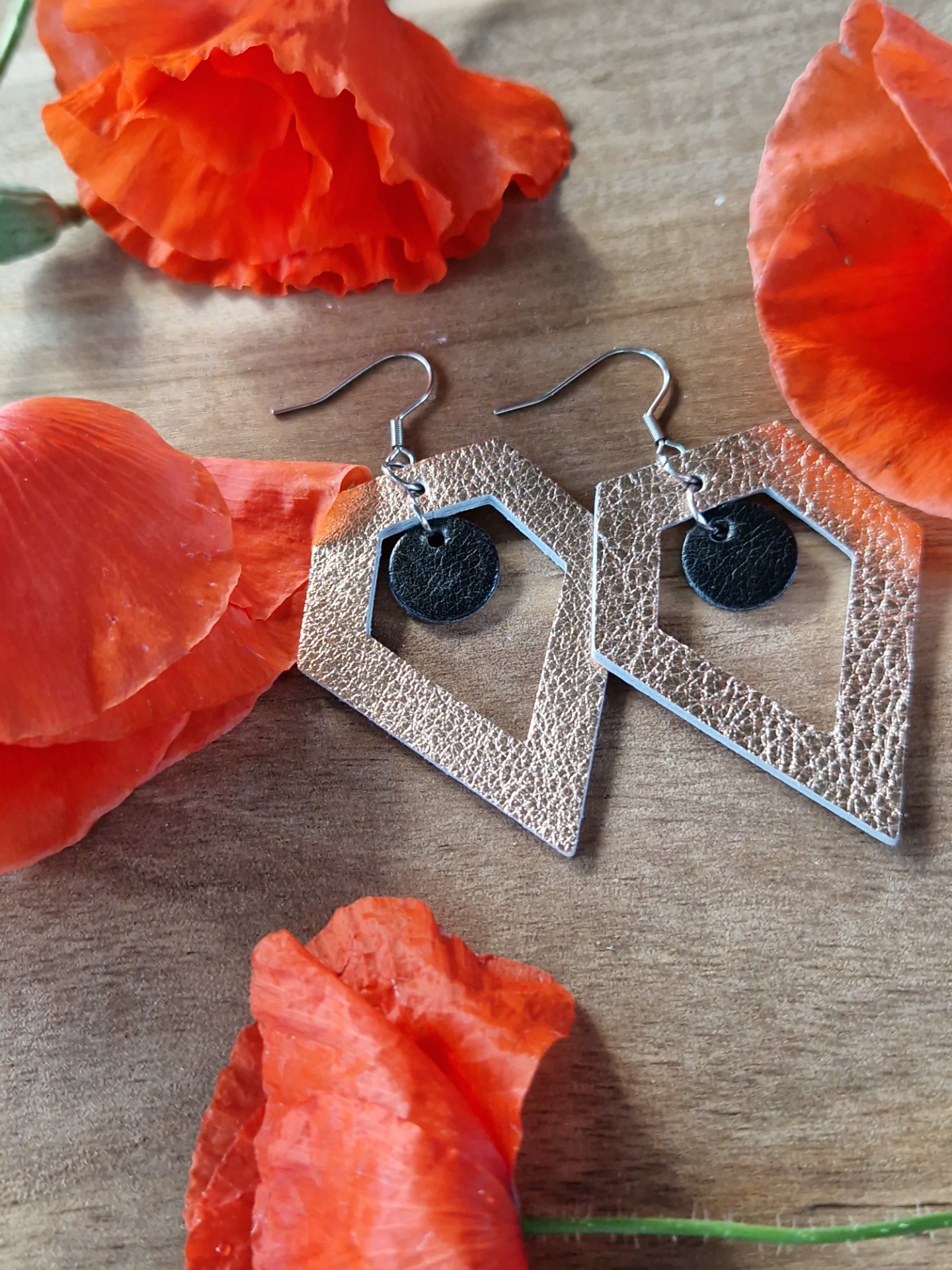 Särmikkäät korvakorut. Ruusukulta on nahkaa, musta jäljitelmänahkaa.