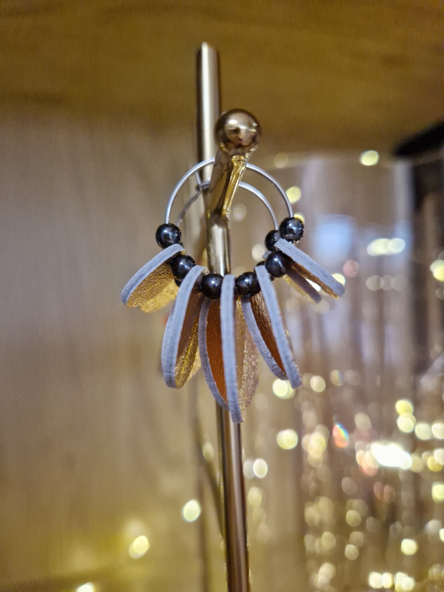 Nahkaiset pallot ja lasihelmet korvakorurenkaassa.